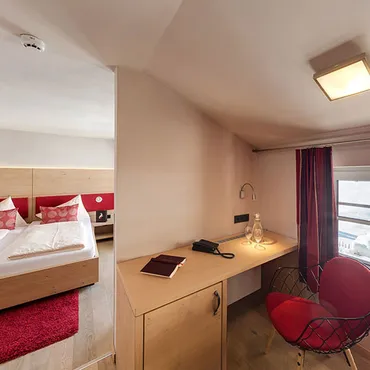 Ifen Cozy hotel room with twin beds, writing desk, red chair, and mountain view through window